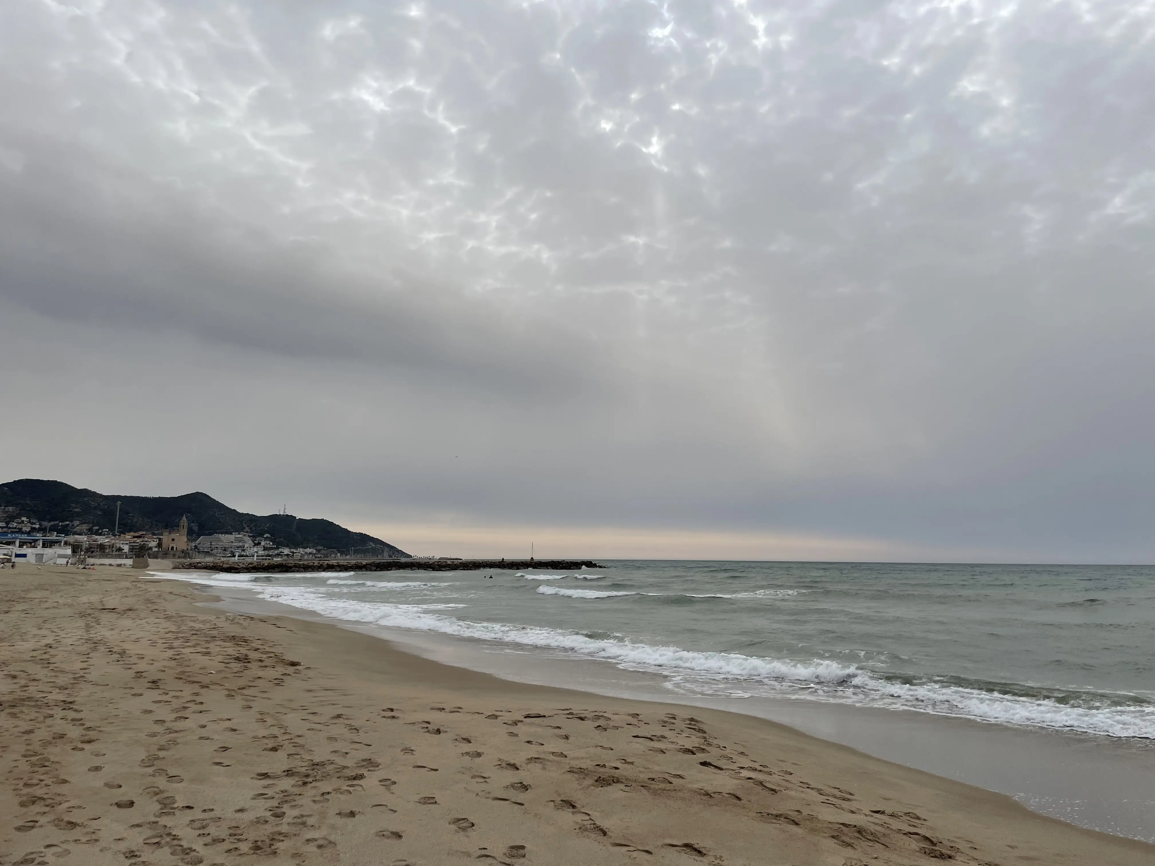 Vista general de la playa de Sitges por la mañana con poca gente y mar en calma